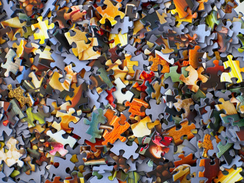 Colorful jigsaw puzzle pieces scattered on a surface, showing a variety of shapes and vibrant patterns