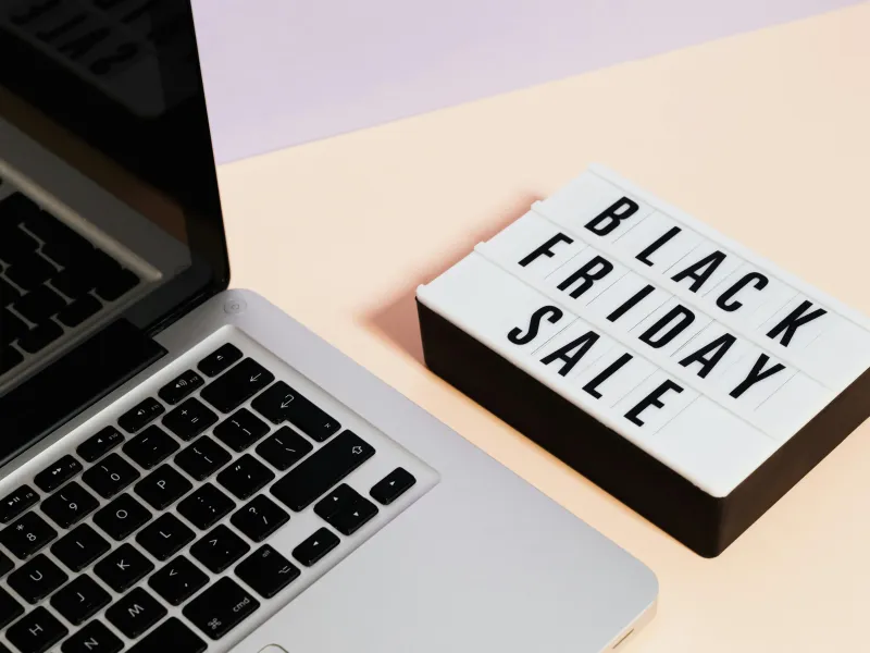 Laptop and lightbox displaying "Black Friday Sale" on a pastel background.